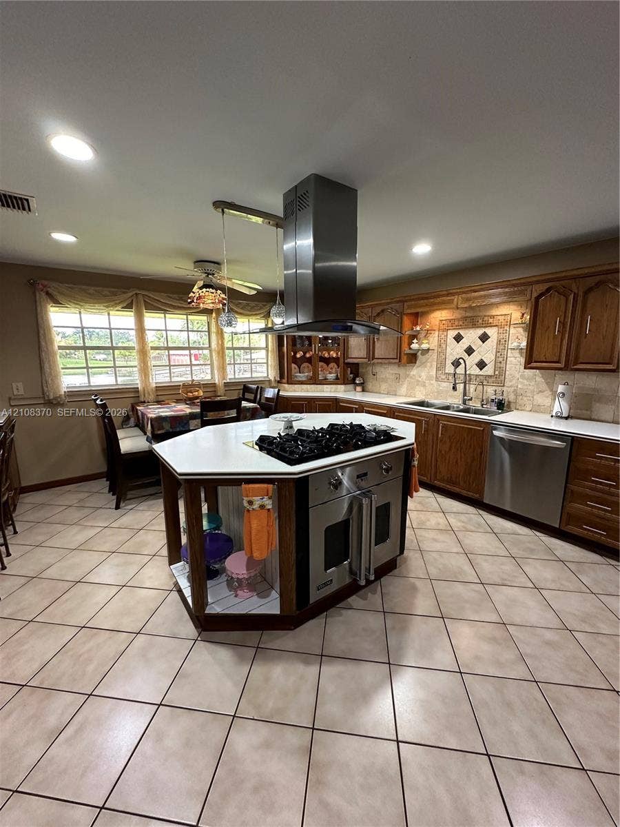 18901 SW 63rd Street, Southwest Ranches, FL 33332 Kitchen featuring a central island with a built-in gas cooktop, stainless steel ventilation hood, wood cabinetry, stone-finish tile flooring, and recessed lighting