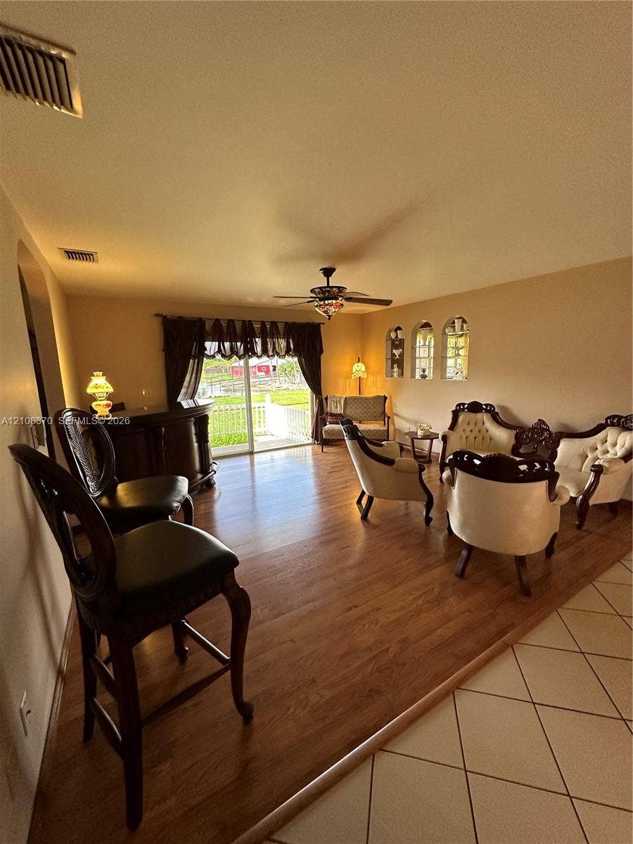 18901 SW 63rd Street, Southwest Ranches, FL 33332 Living area featuring wood-finish flooring, built-in wet bar, arched wall niches, sliding glass door, and a ceiling fan