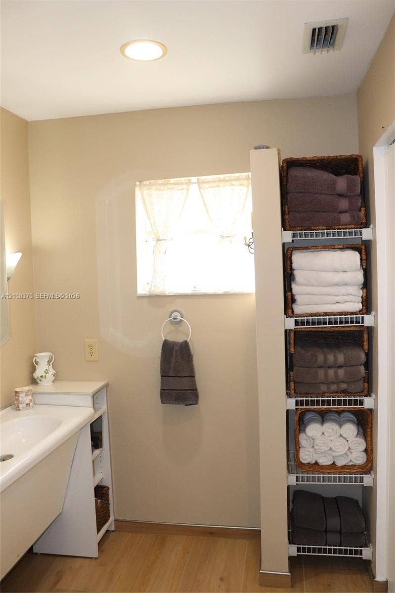 18901 SW 63rd Street, Southwest Ranches, FL 33332 Built-in white vanity with integrated basin, light-toned wood-finish flooring, and floor-to-ceiling white wire shelving