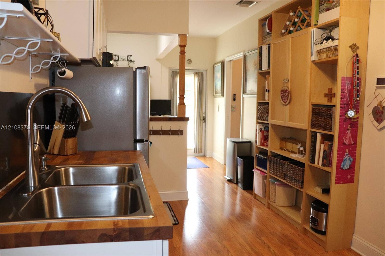 18901 SW 63rd Street, Southwest Ranches, FL 33332 Kitchen featuring a butcher block countertop, stainless steel dual-basin sink with a high-arch faucet, wood-finish flooring, and floor-to-ceiling built-in cabinetry