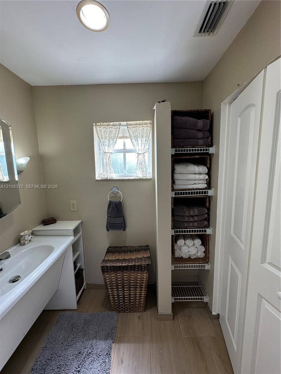 18901 SW 63rd Street, Southwest Ranches, FL 33332 Bathroom featuring a vanity with an integrated sink, built-in wire shelving, wood-finish flooring, and a window with a sash lock