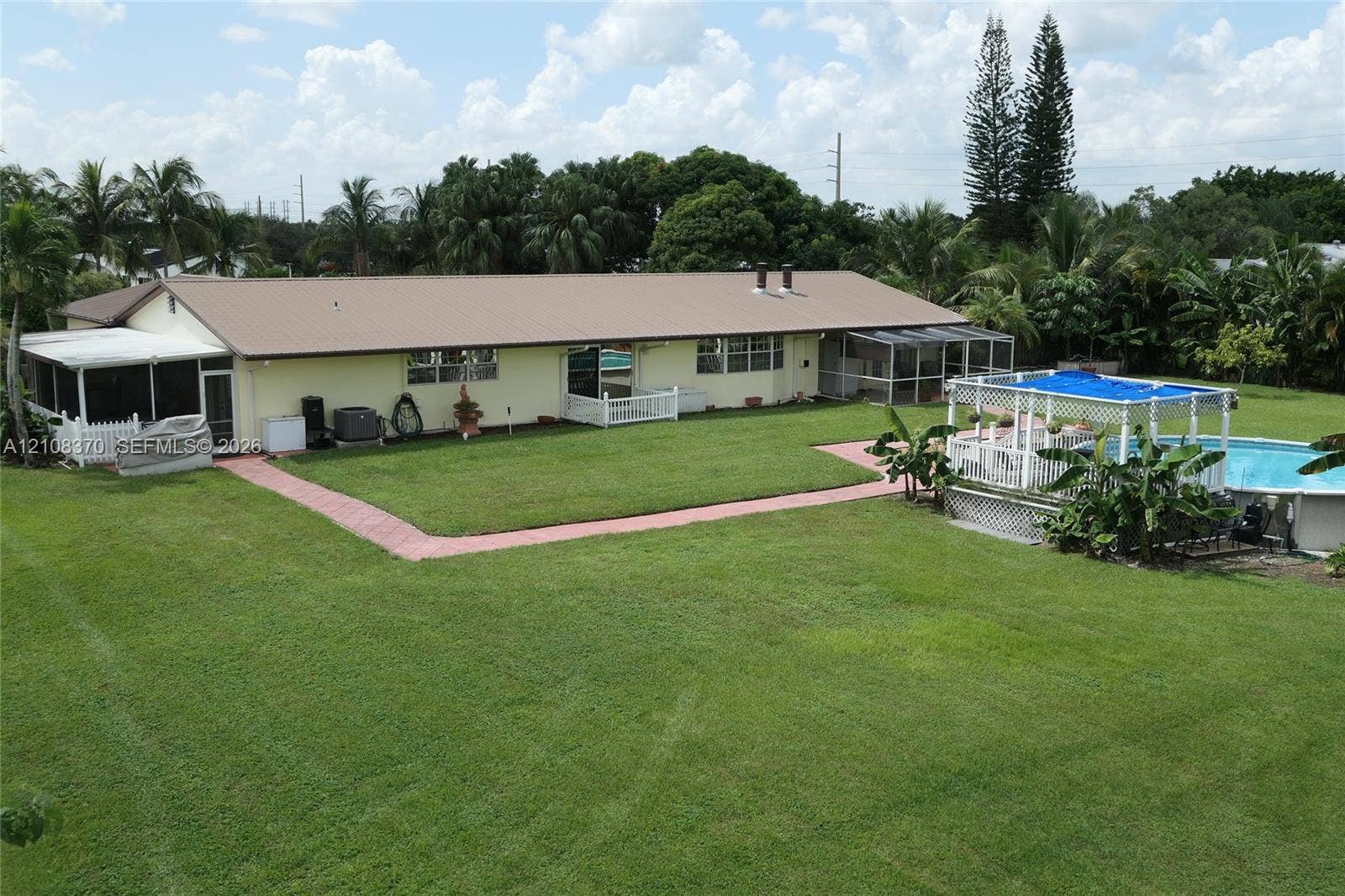18901 SW 63rd Street, Southwest Ranches, FL 33332 Expansive backyard featuring a manicured lawn, inground swimming pool with a pergola, screened-in porch, and concrete paver walkways