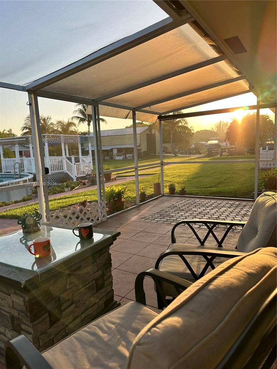18901 SW 63rd Street, Southwest Ranches, FL 33332 Screen-enclosed patio featuring a paver floor, stone-finish base, and metal framing