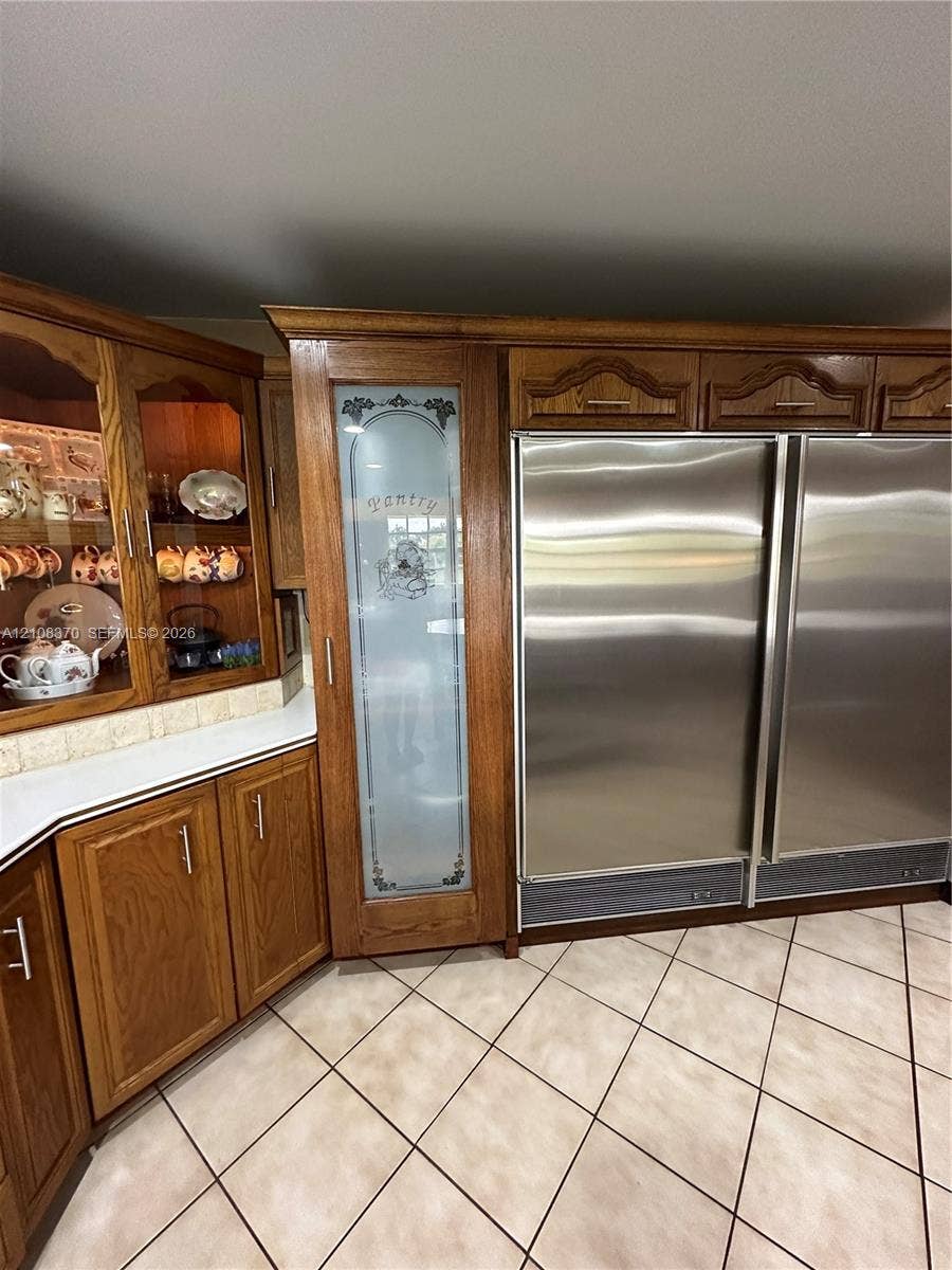 18901 SW 63rd Street, Southwest Ranches, FL 33332 Custom wood cabinetry, floor-to-ceiling pantry with etched glass door, integrated side-by-side stainless steel refrigeration, and ceramic tile flooring