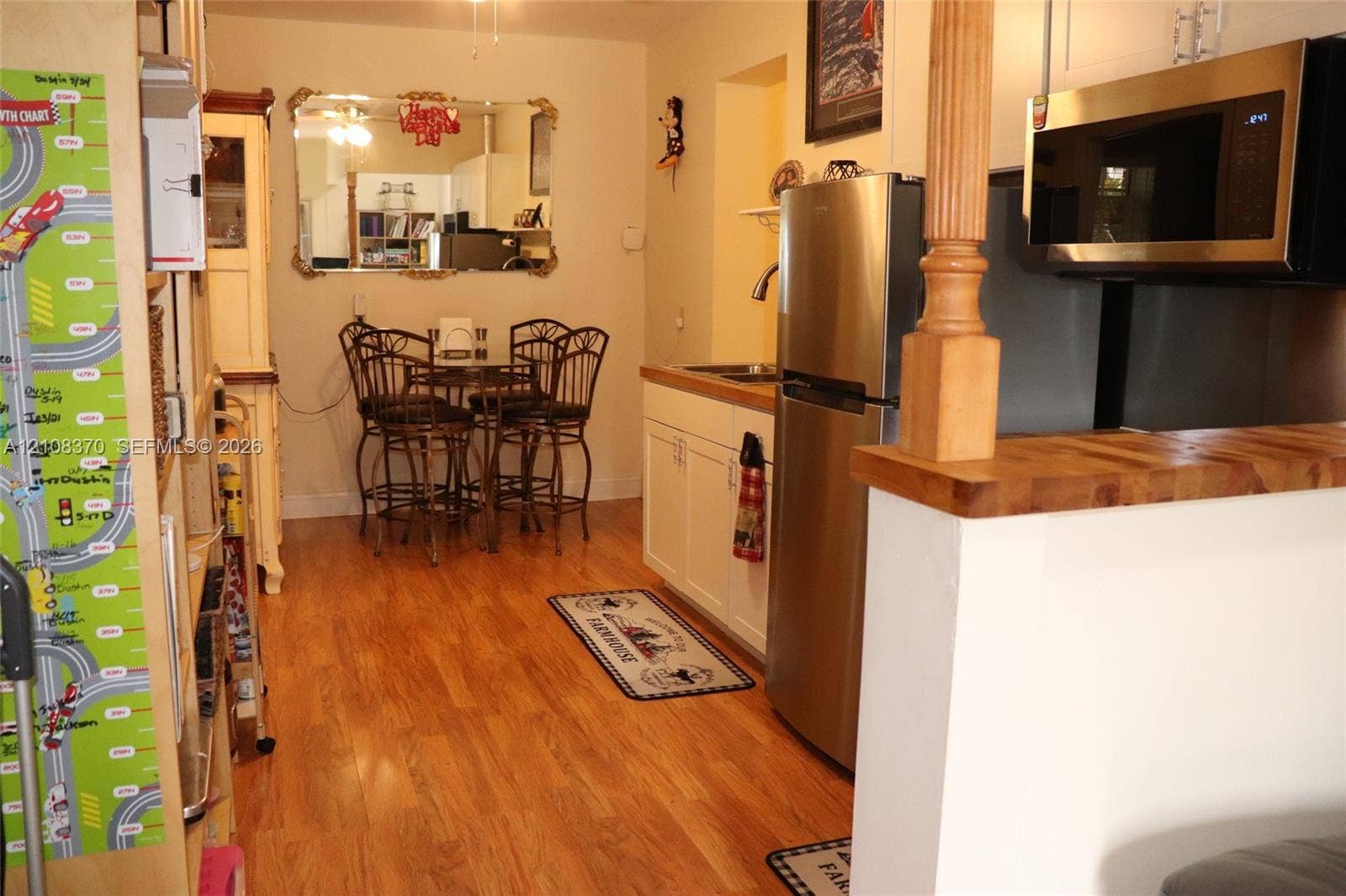 18901 SW 63rd Street, Southwest Ranches, FL 33332 Kitchen featuring stainless steel appliances, wood-finish flooring, white cabinetry, and a wood-topped peninsula with a decorative post