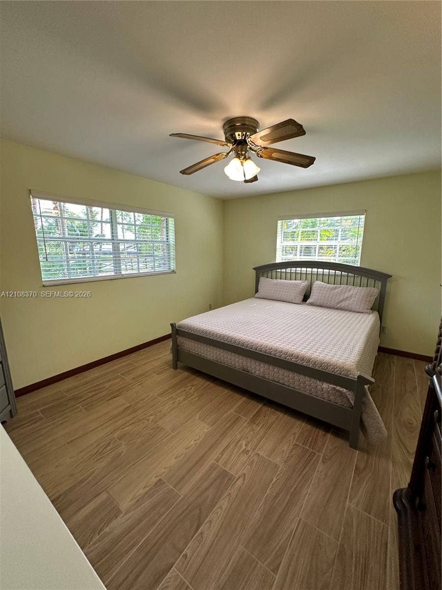 18901 SW 63rd Street, Southwest Ranches, FL 33332 Interior space featuring wood-finish tile flooring, two windows with horizontal blinds, and a multi-blade ceiling fan with integrated lighting