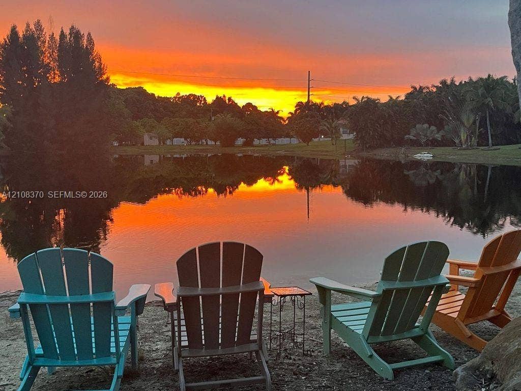 18901 SW 63rd Street, Southwest Ranches, FL 33332 Waterfront property featuring a pond, mature trees, and a sunset backdrop