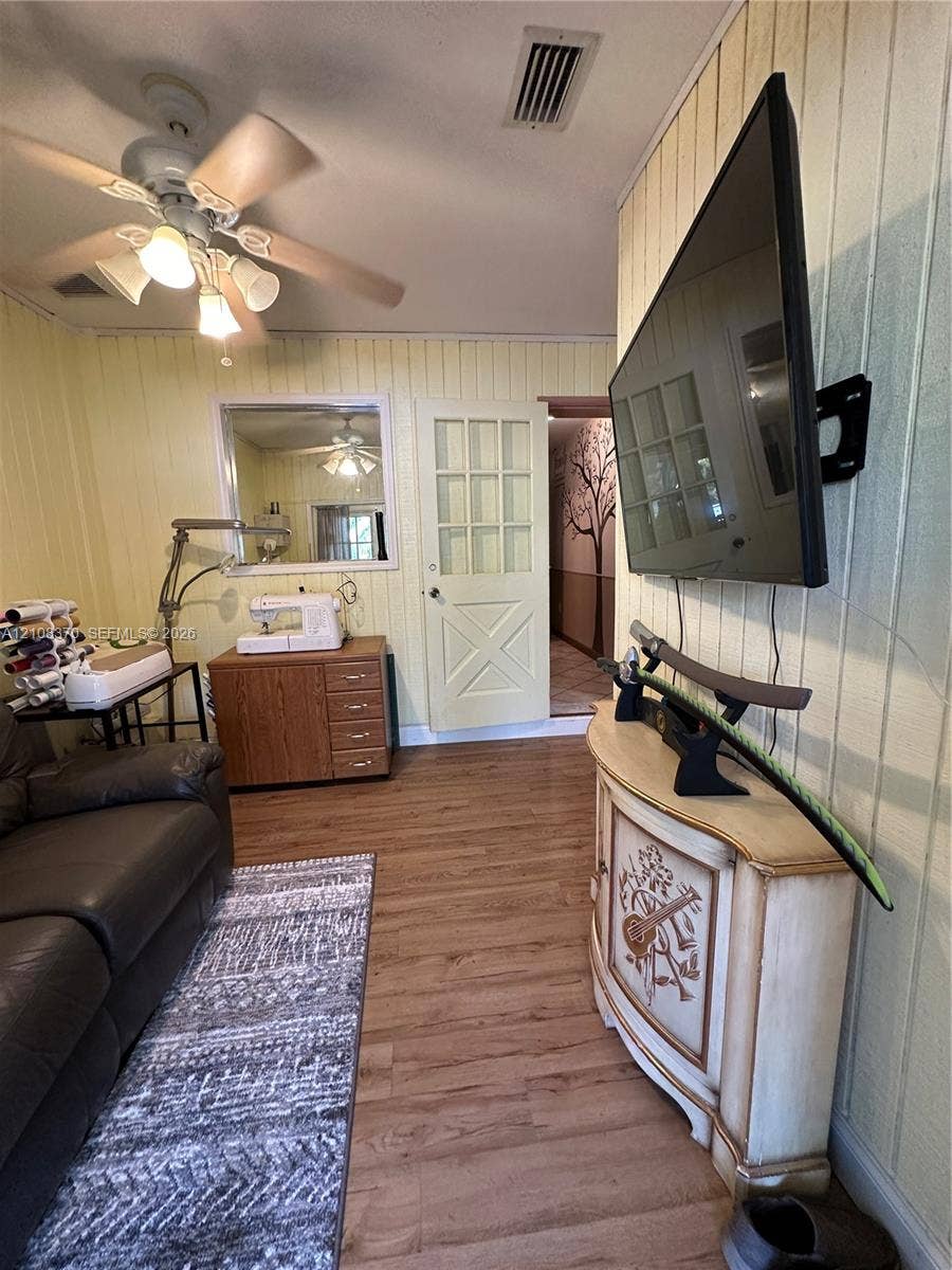 18901 SW 63rd Street, Southwest Ranches, FL 33332 Interior space featuring wood-finish flooring, vertical panel wall detailing, and a multi-pane door with a cross-buck design