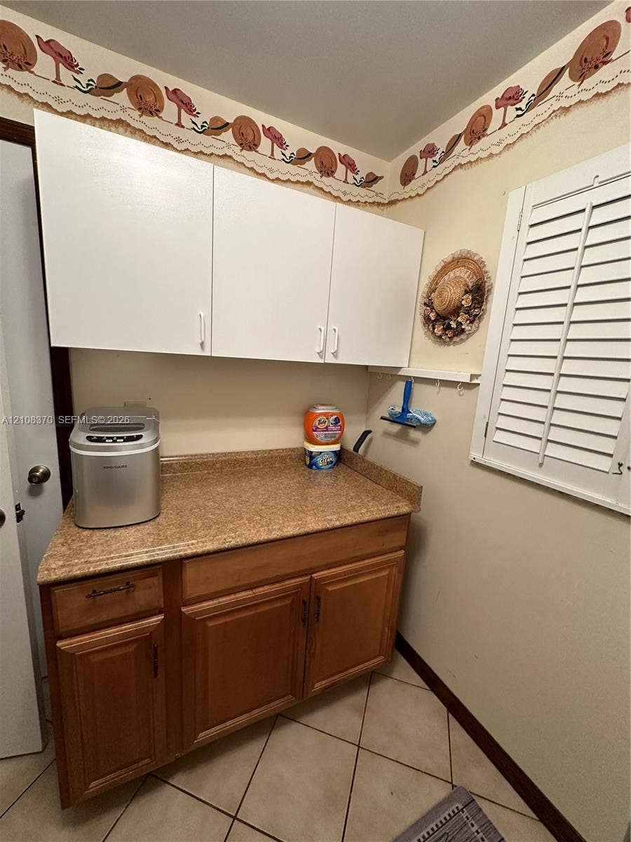 18901 SW 63rd Street, Southwest Ranches, FL 33332 Custom cabinetry featuring white upper storage and wood-finish lower base cabinets with stone-finish countertops and white plantation shutters