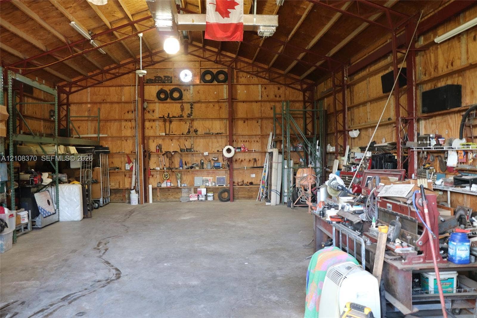 18901 SW 63rd Street, Southwest Ranches, FL 33332 Expansive interior workshop featuring exposed structural steel framing, high vaulted ceilings with integrated lighting, concrete flooring, and plywood wall paneling