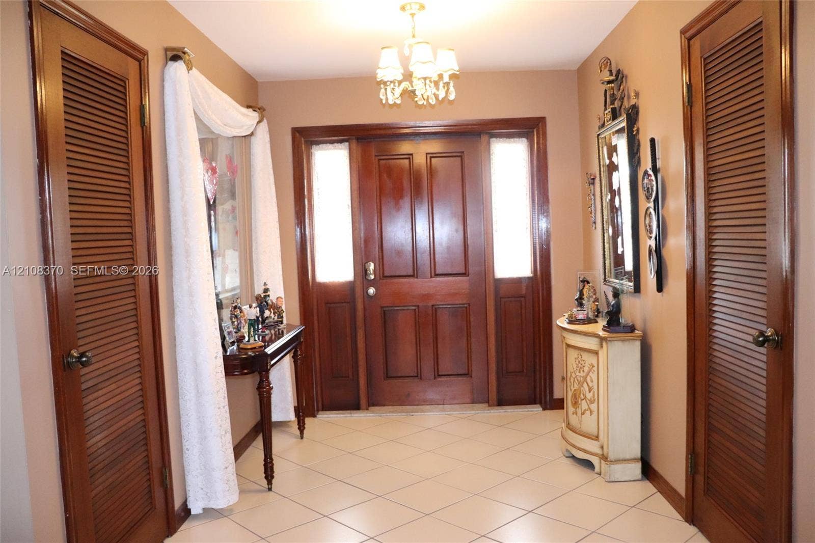 18901 SW 63rd Street, Southwest Ranches, FL 33332 Foyer featuring a solid wood entry door with flanking sidelights, ceramic tile flooring, and dual wood-finished louvered closet doors