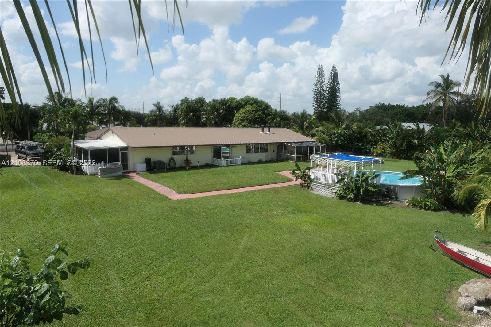 18901 SW 63rd Street, Southwest Ranches, FL 33332 Expansive backyard featuring a large grass lawn, screened-in patio, and an above-ground swimming pool with a hardscape surround