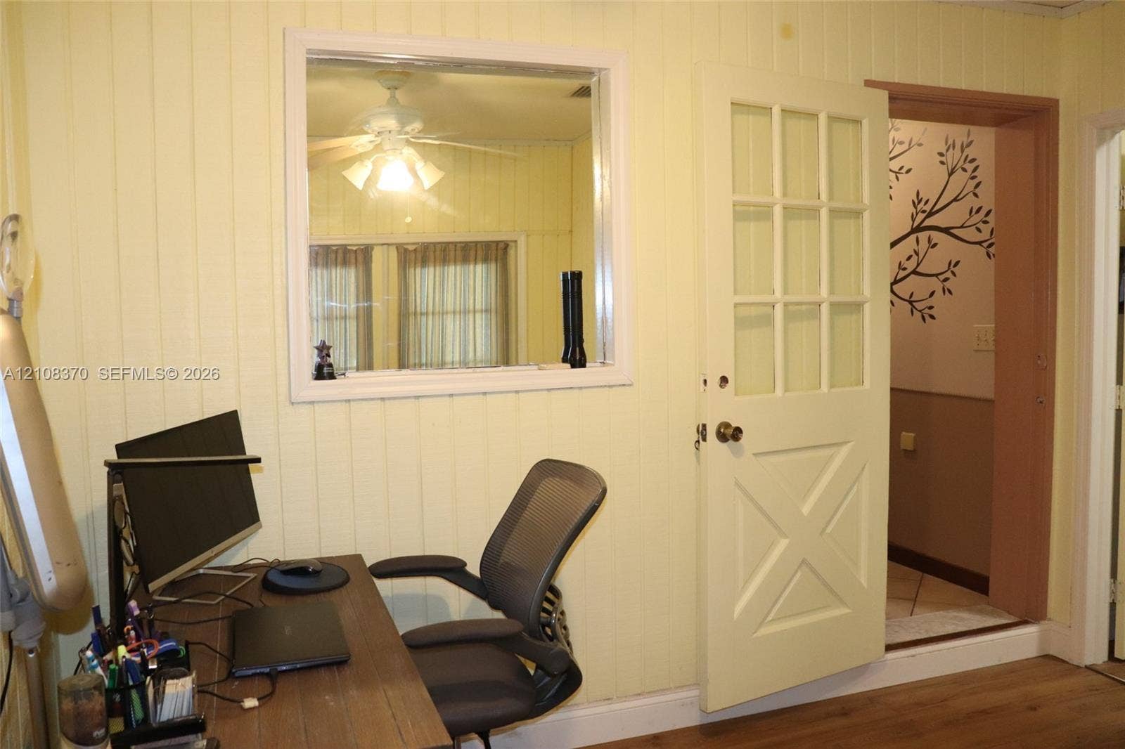 18901 SW 63rd Street, Southwest Ranches, FL 33332 Vertical wood-panel walls, interior fixed-pane window, nine-pane glass and wood door with cross-buck paneling, and wood-finish flooring