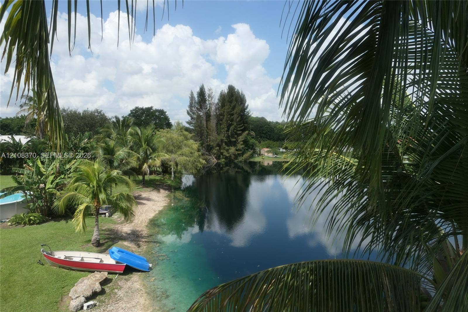 18901 SW 63rd Street, Southwest Ranches, FL 33332 Waterfront property featuring a private shoreline, expansive grassy lawn, and mature palm trees