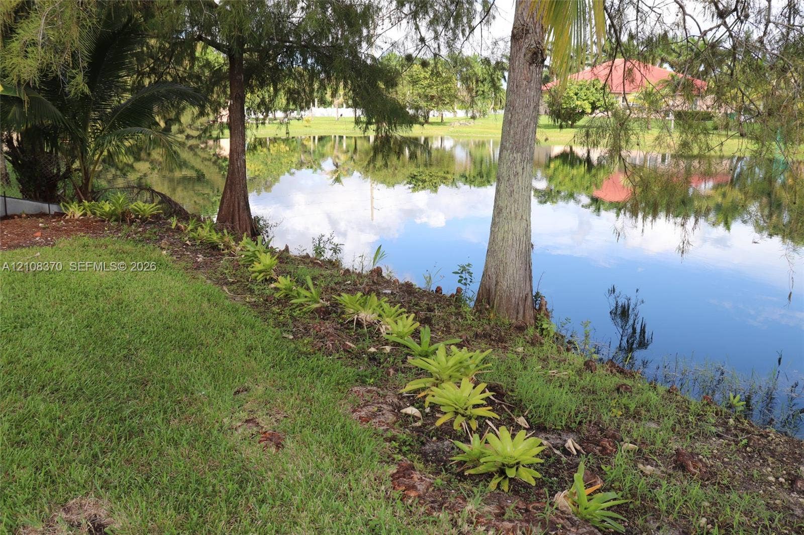18901 SW 63rd Street, Southwest Ranches, FL 33332 Waterfront lot featuring mature trees, landscaped border plantings, and expansive lawn