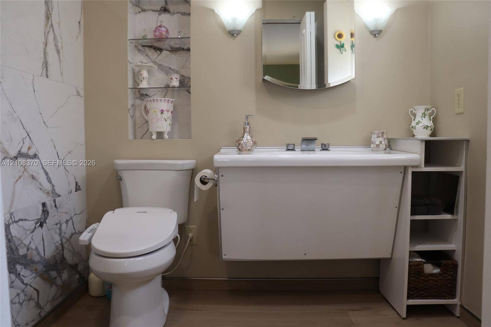 18901 SW 63rd Street, Southwest Ranches, FL 33332 Wall-mounted sink with integrated storage, full-height stone-patterned tile wall, recessed shelving, and dual wall-mounted light fixtures