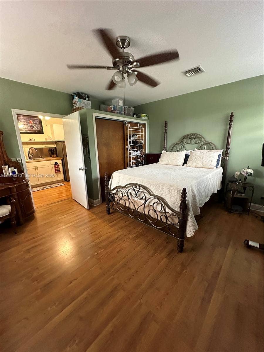 18901 SW 63rd Street, Southwest Ranches, FL 33332 Room featuring wood-finish flooring, a ceiling fan with integrated lighting, and a reach-in closet with wood-finish sliding doors