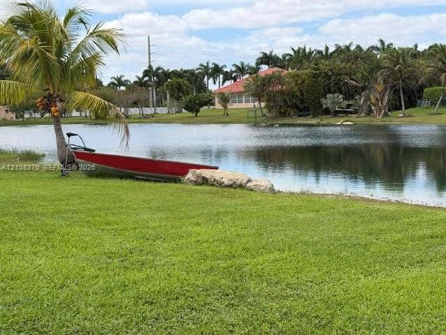 18901 SW 63rd Street, Southwest Ranches, FL 33332 Waterfront lot featuring a manicured lawn, natural pond, boulder accent, and mature palm trees