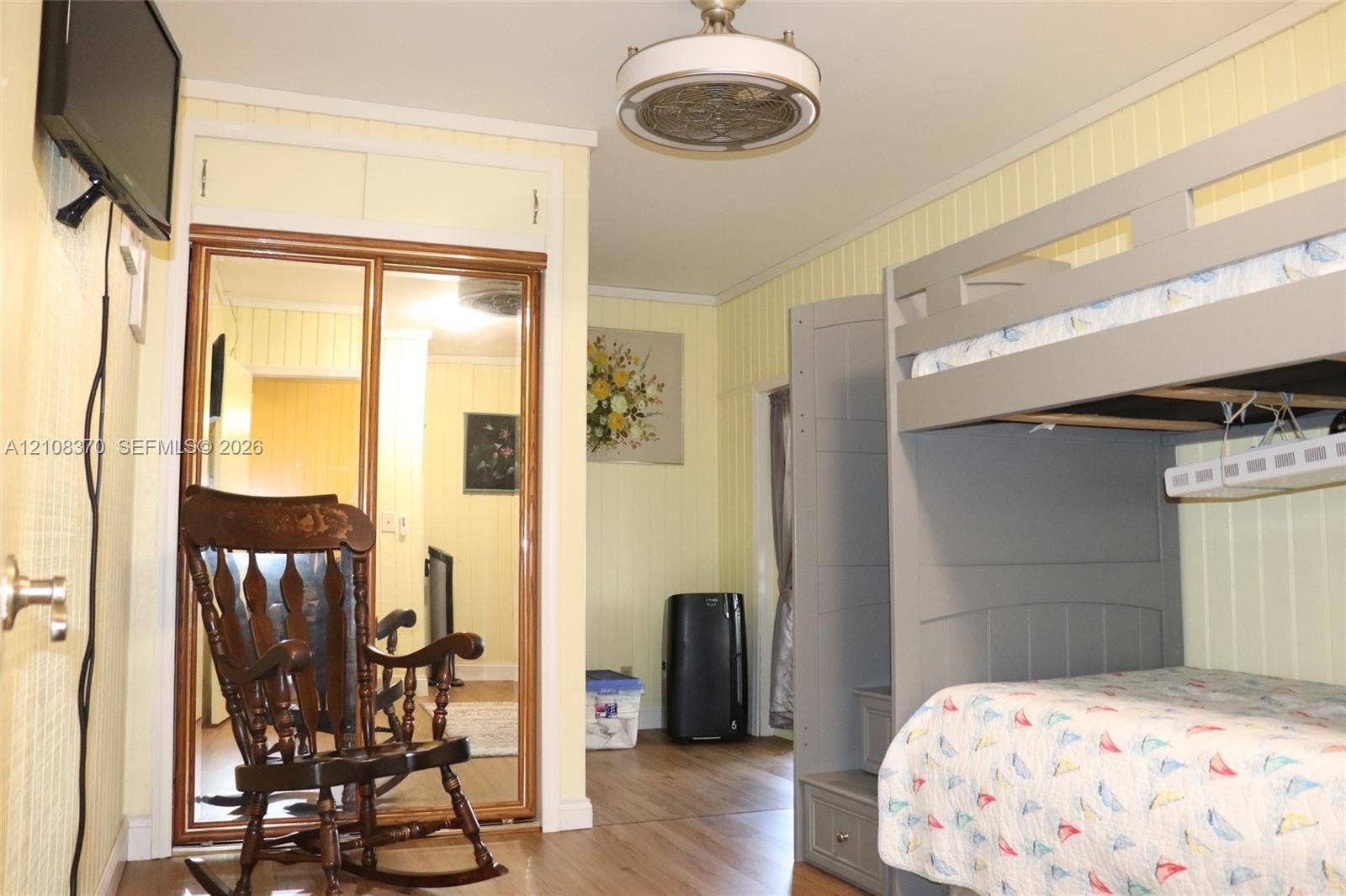 18901 SW 63rd Street, Southwest Ranches, FL 33332 Wood-finish flooring, vertical panel wall detailing, mirrored sliding closet doors with built-in overhead storage, and a ceiling-mounted light fixture
