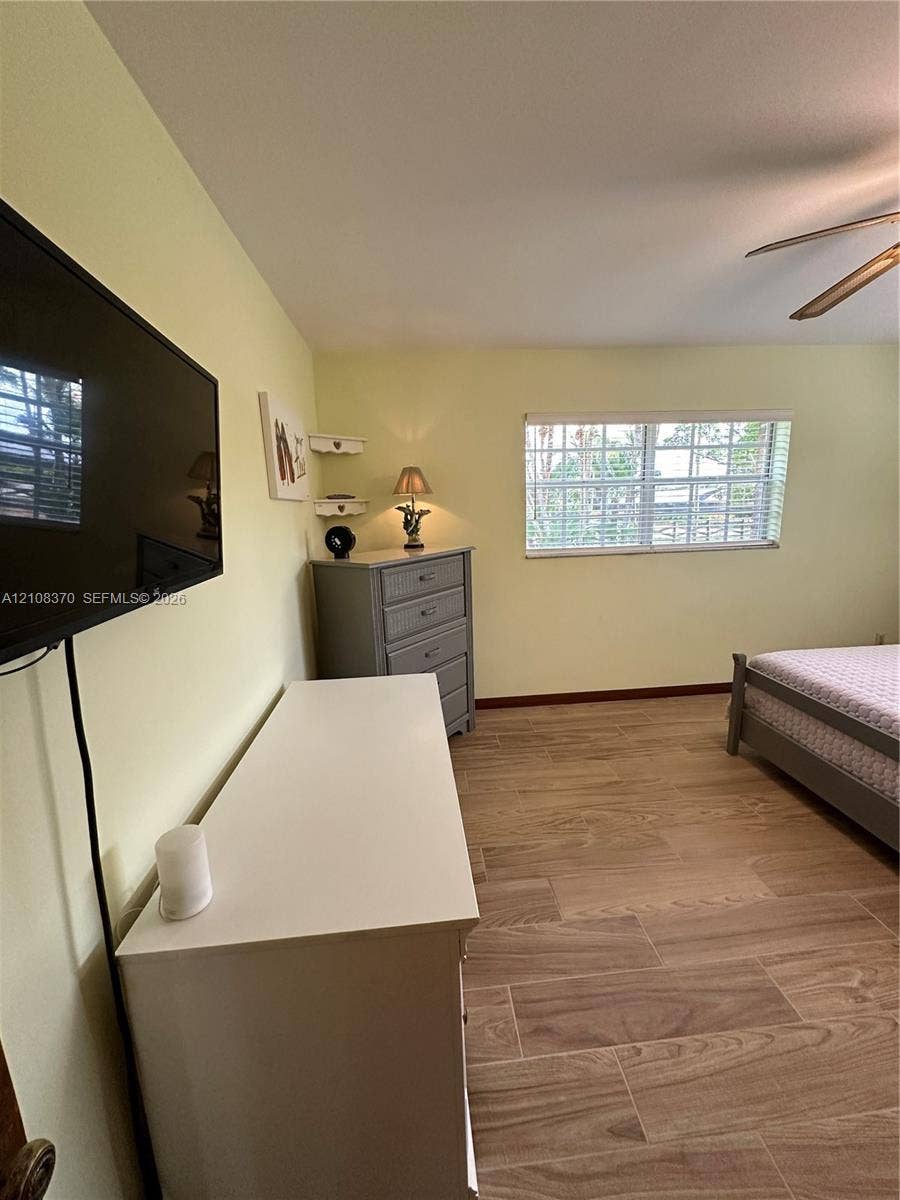18901 SW 63rd Street, Southwest Ranches, FL 33332 Wood-finish ceramic tile flooring, horizontal blinds, ceiling fan, and wall-mounted television bracket