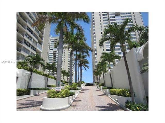 Concrete high-rise exteriors featuring a paver driveway, tiered concrete planter boxes, and mature palm trees