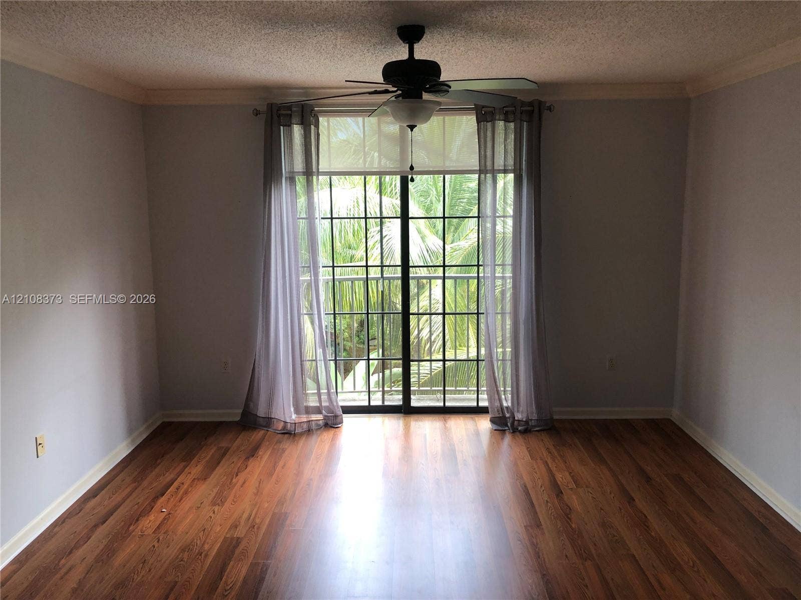 1900 Van Buren Street, #411B, Hollywood, FL 33020 Wood-finish flooring, ceiling fan with integrated light fixture, and black-framed sliding glass doors opening to an exterior railing