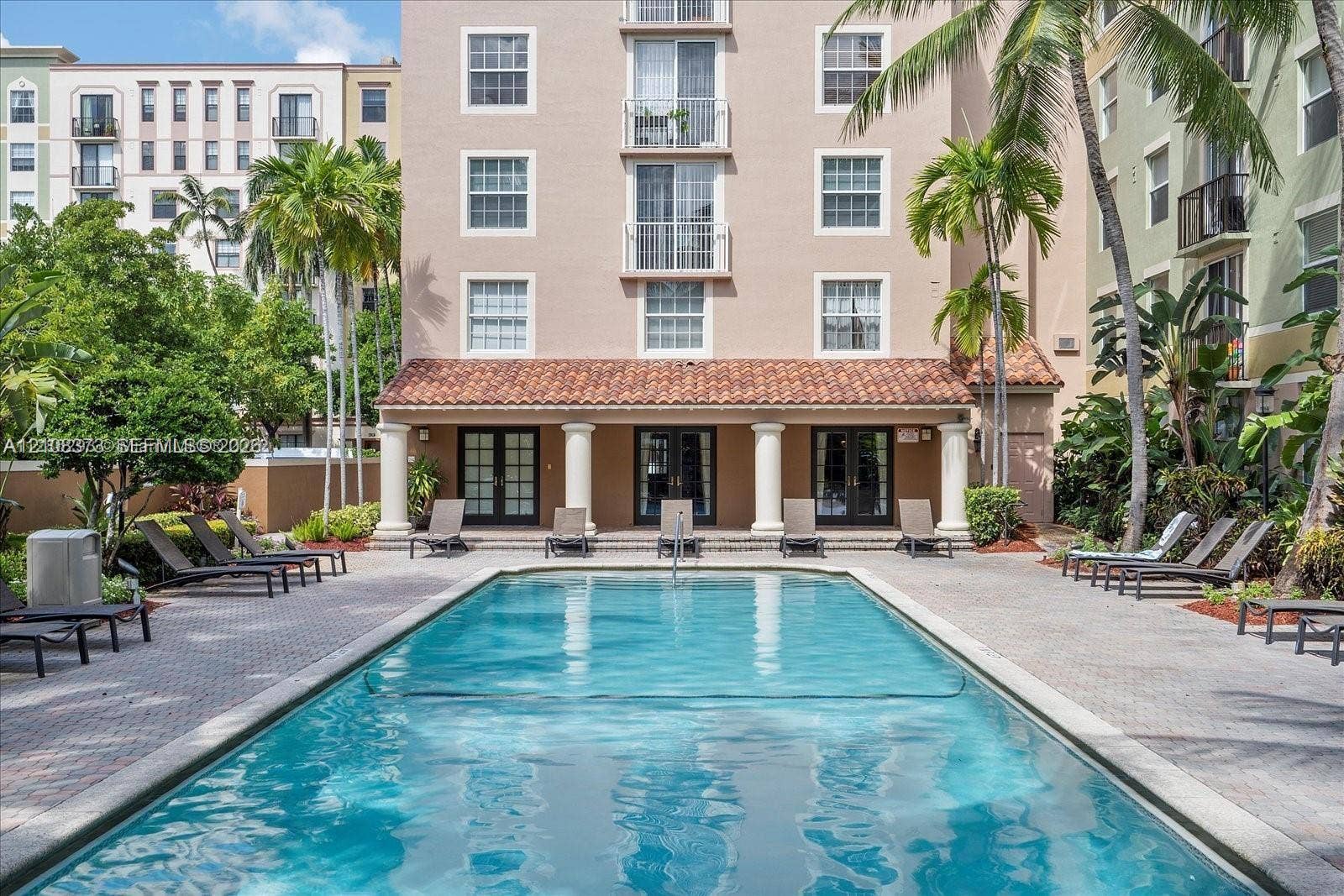 1900 Van Buren Street, #411B, Hollywood, FL 33020 Outdoor swimming pool featuring a paver stone deck, classic architectural columns, a terra cotta tile roof, and multiple sets of French doors
