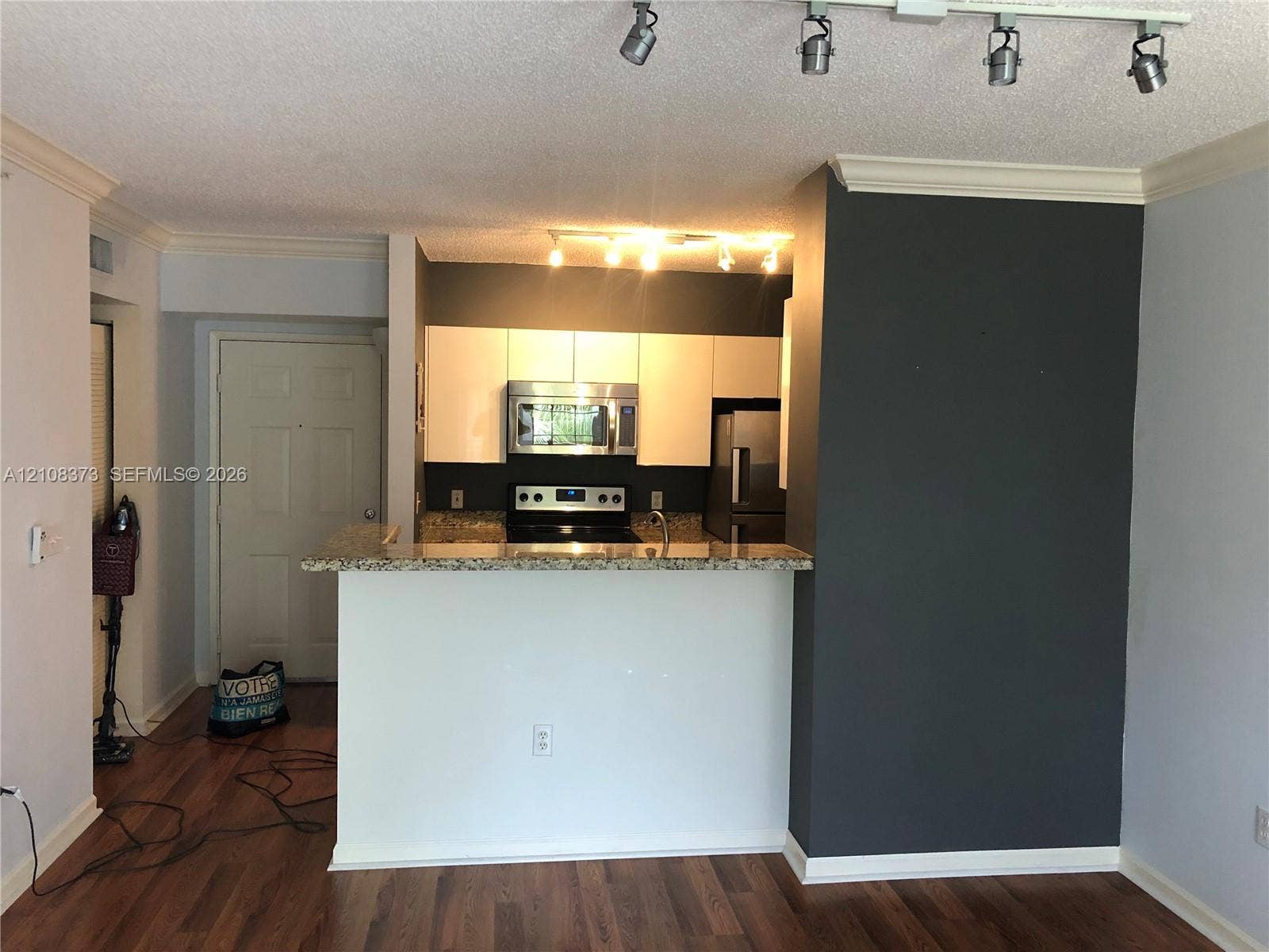 1900 Van Buren Street, #411B, Hollywood, FL 33020 Kitchen featuring white cabinetry, stone-finish countertops, stainless steel appliances, breakfast bar, and adjustable track lighting
