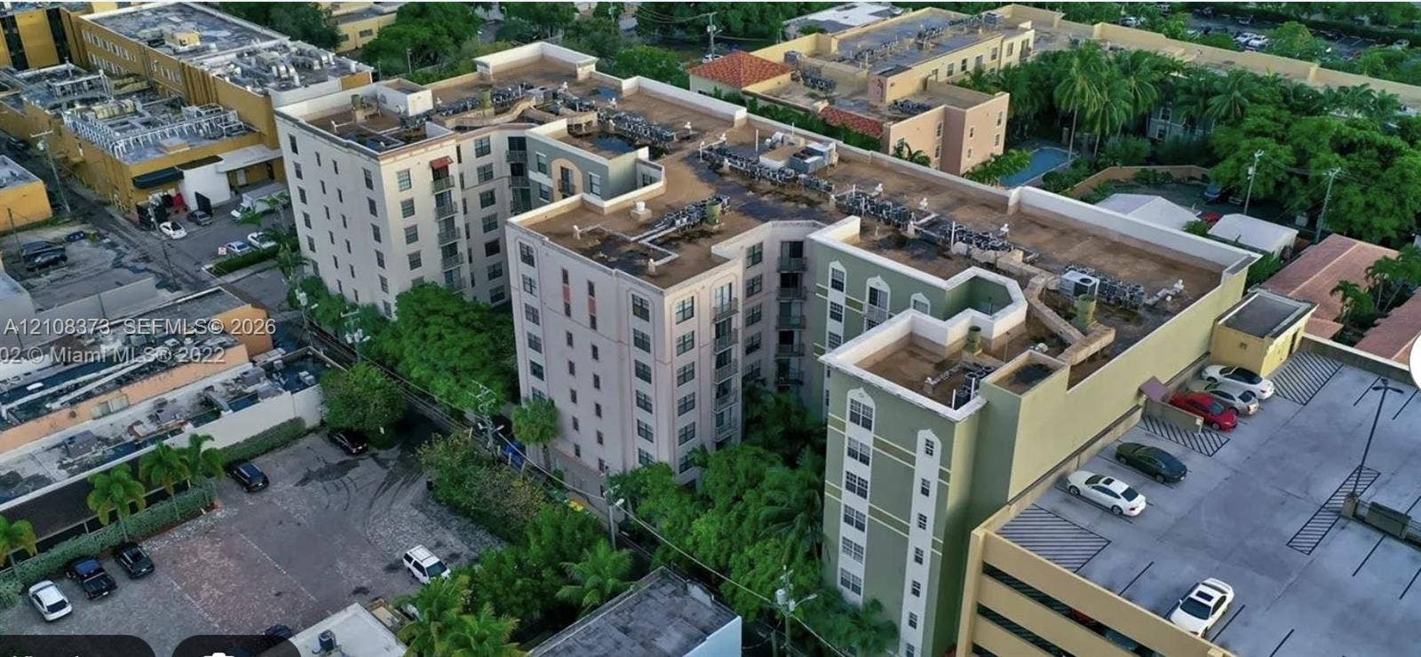 1900 Van Buren Street, #411B, Hollywood, FL 33020 Multi-story complex featuring a structured exterior, arched window details, dedicated surface parking, and manicured perimeter landscaping