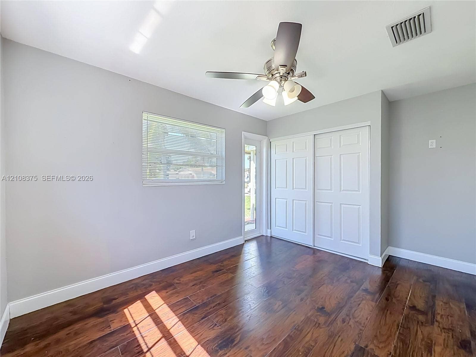 3330 NE 14th Terrace, Pompano Beach, FL 33064 Room featuring wood-finish flooring, a ceiling fan with integrated lighting, a sliding closet with paneled doors, and a glass-paneled exterior door