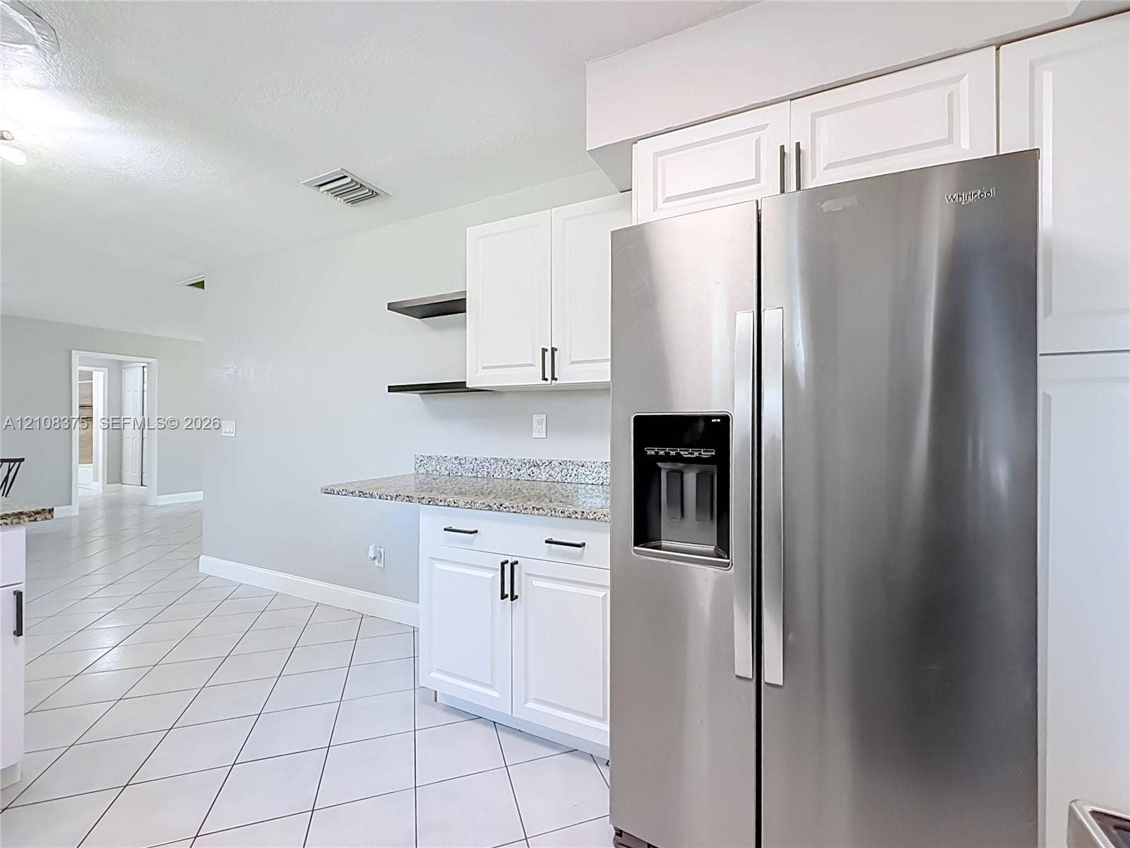 3330 NE 14th Terrace, Pompano Beach, FL 33064 Kitchen featuring white shaker-style cabinetry, stainless steel side-by-side refrigerator, stone-composite countertops, open shelving, and neutral ceramic tile flooring