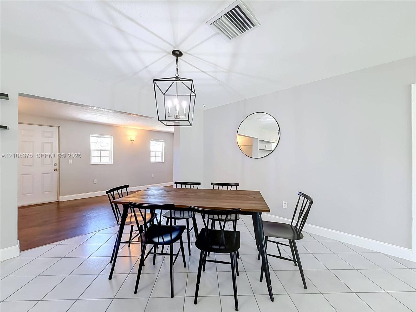 3330 NE 14th Terrace, Pompano Beach, FL 33064 Geometric metal lantern pendant light, circular wall-mounted mirror, neutral interior paint, ceramic tile flooring, and multi-panel solid core door