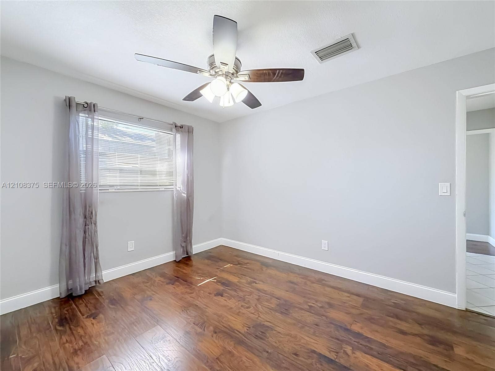 3330 NE 14th Terrace, Pompano Beach, FL 33064 Wood-finish flooring, neutral wall tones, and a ceiling fan with integrated lighting