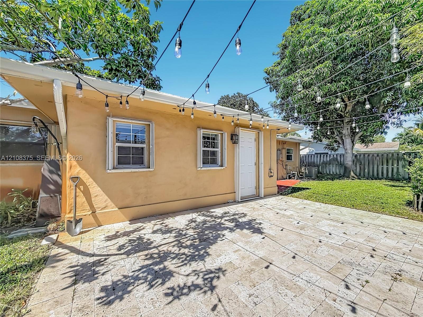 3330 NE 14th Terrace, Pompano Beach, FL 33064 Exterior patio featuring stone paver flooring, string lighting, and direct access to the backyard