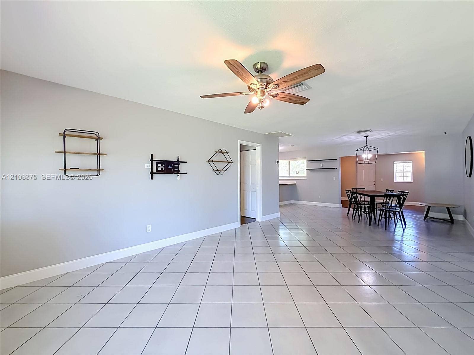 3330 NE 14th Terrace, Pompano Beach, FL 33064 Large format ceramic tile flooring, neutral wall tones, multi-blade ceiling fan with integrated lighting, and geometric wall-mounted shelving units