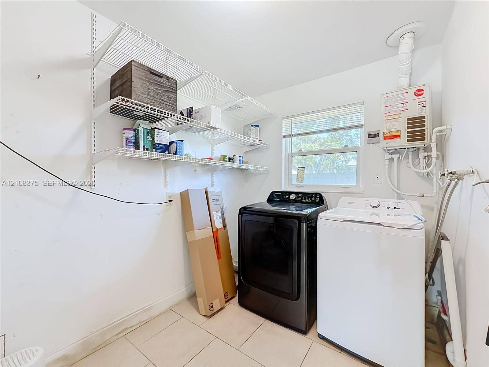 3330 NE 14th Terrace, Pompano Beach, FL 33064 Laundry area featuring tile flooring, multi-tiered wire shelving, a window with horizontal blinds, and an integrated tankless water heater