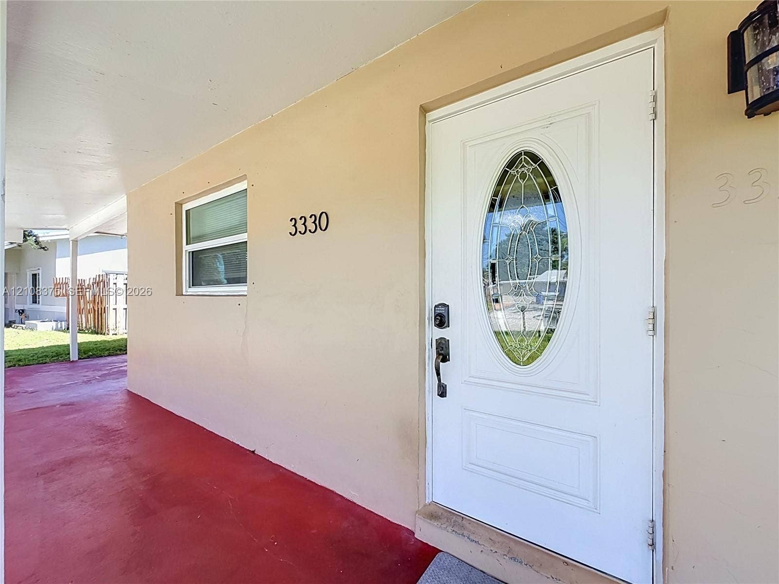3330 NE 14th Terrace, Pompano Beach, FL 33064 Covered entryway featuring a white paneled door with an oval glass insert, exterior wall-mounted lighting, and a painted concrete porch