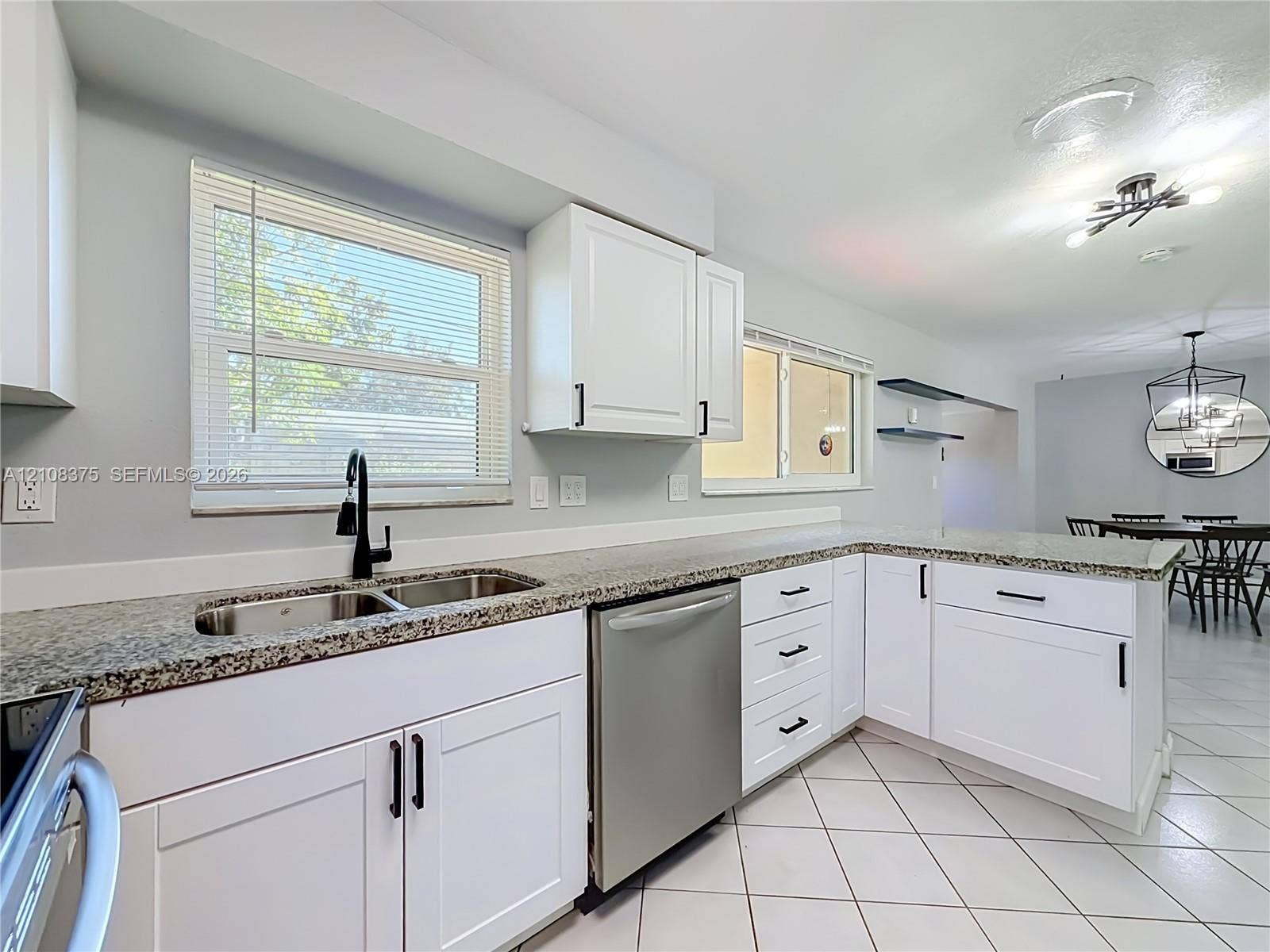 3330 NE 14th Terrace, Pompano Beach, FL 33064 Kitchen featuring white shaker-style cabinetry, stone-finish countertops, stainless steel dishwasher, double-basin undermount sink with matte black faucet, and ceramic tile flooring