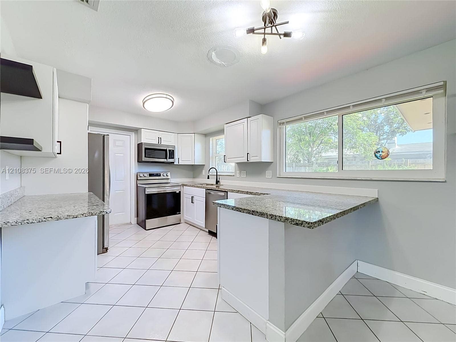 3330 NE 14th Terrace, Pompano Beach, FL 33064 Kitchen featuring white cabinetry, stone-finish countertops, stainless steel appliances, a tile floor, and a multi-light chandelier