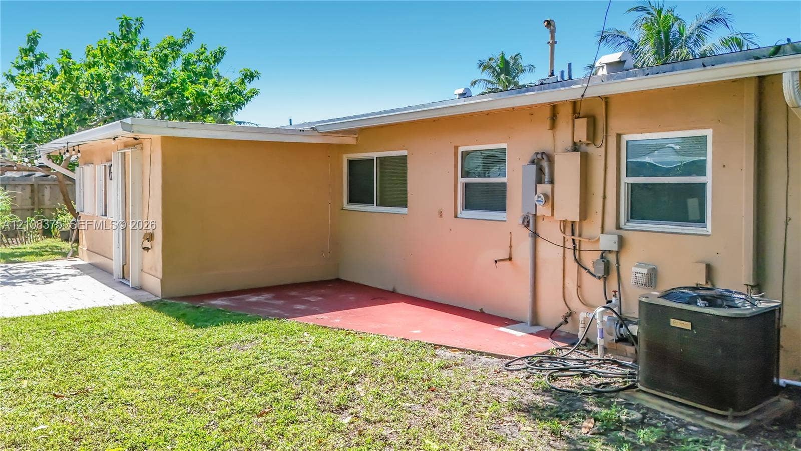 3330 NE 14th Terrace, Pompano Beach, FL 33064 Exterior view featuring a concrete patio, horizontal sliding windows, and a dedicated central air conditioning unit