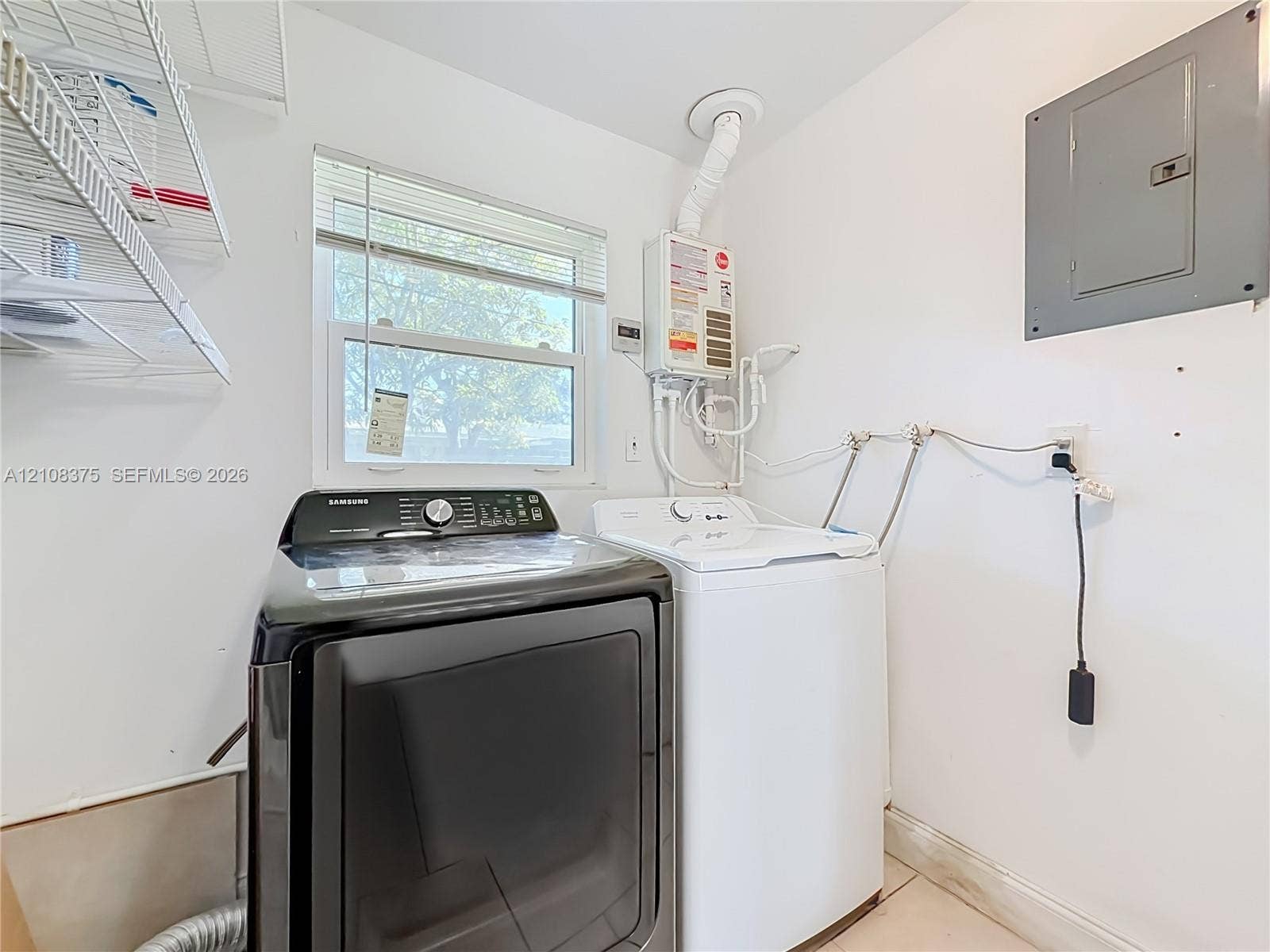 3330 NE 14th Terrace, Pompano Beach, FL 33064 Laundry area featuring a tankless water heater, electrical panel, and mounted wire shelving