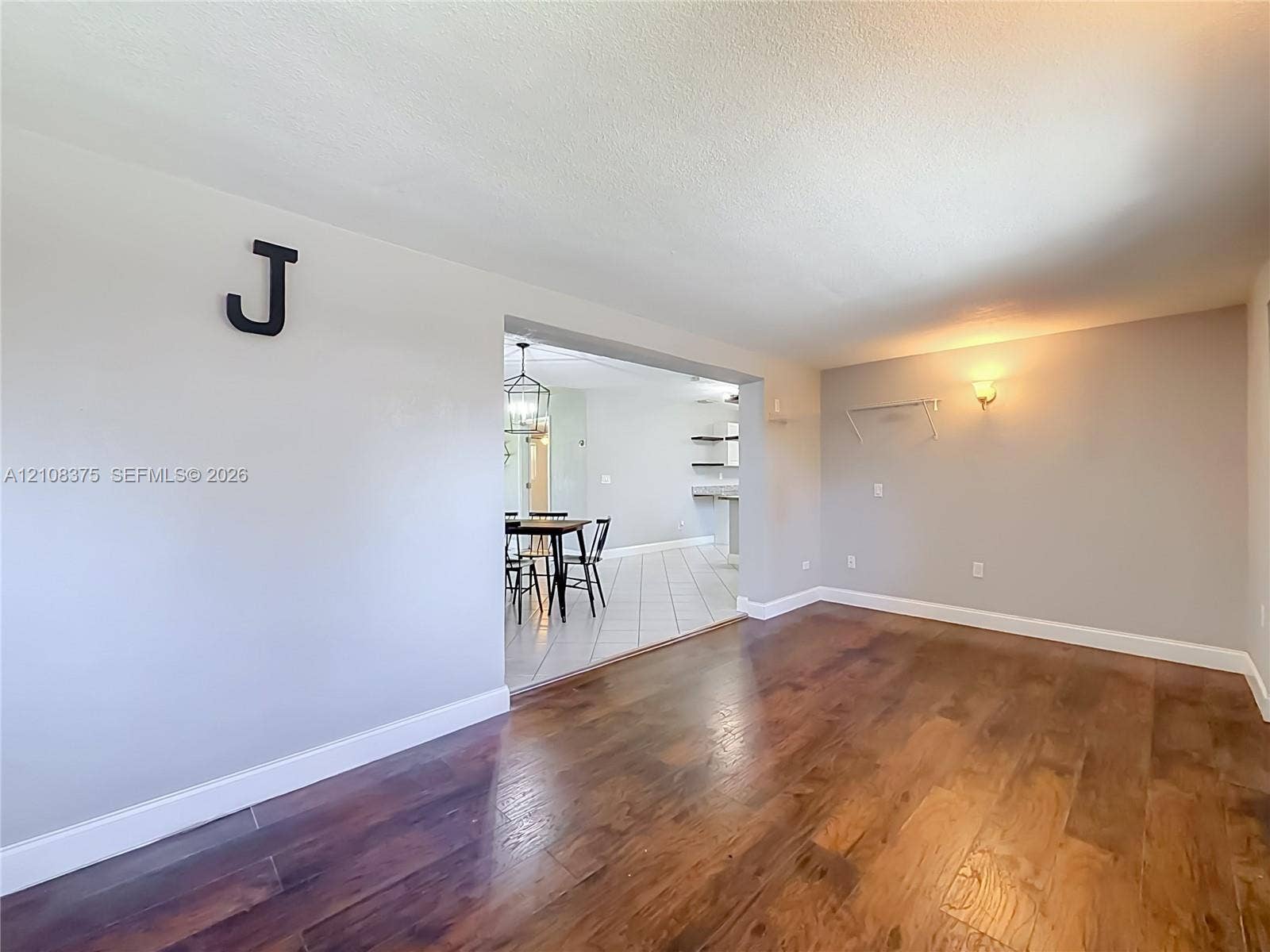 3330 NE 14th Terrace, Pompano Beach, FL 33064 Room featuring wood-finish flooring, neutral wall paint, and wall-mounted lighting