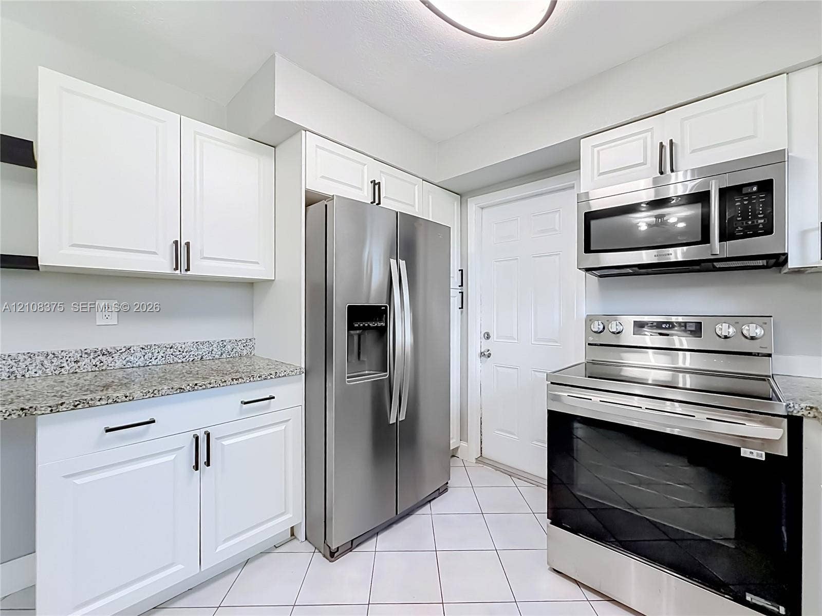 3330 NE 14th Terrace, Pompano Beach, FL 33064 Kitchen featuring white shaker-style cabinetry, stone countertops, stainless steel appliances, and ceramic tile flooring