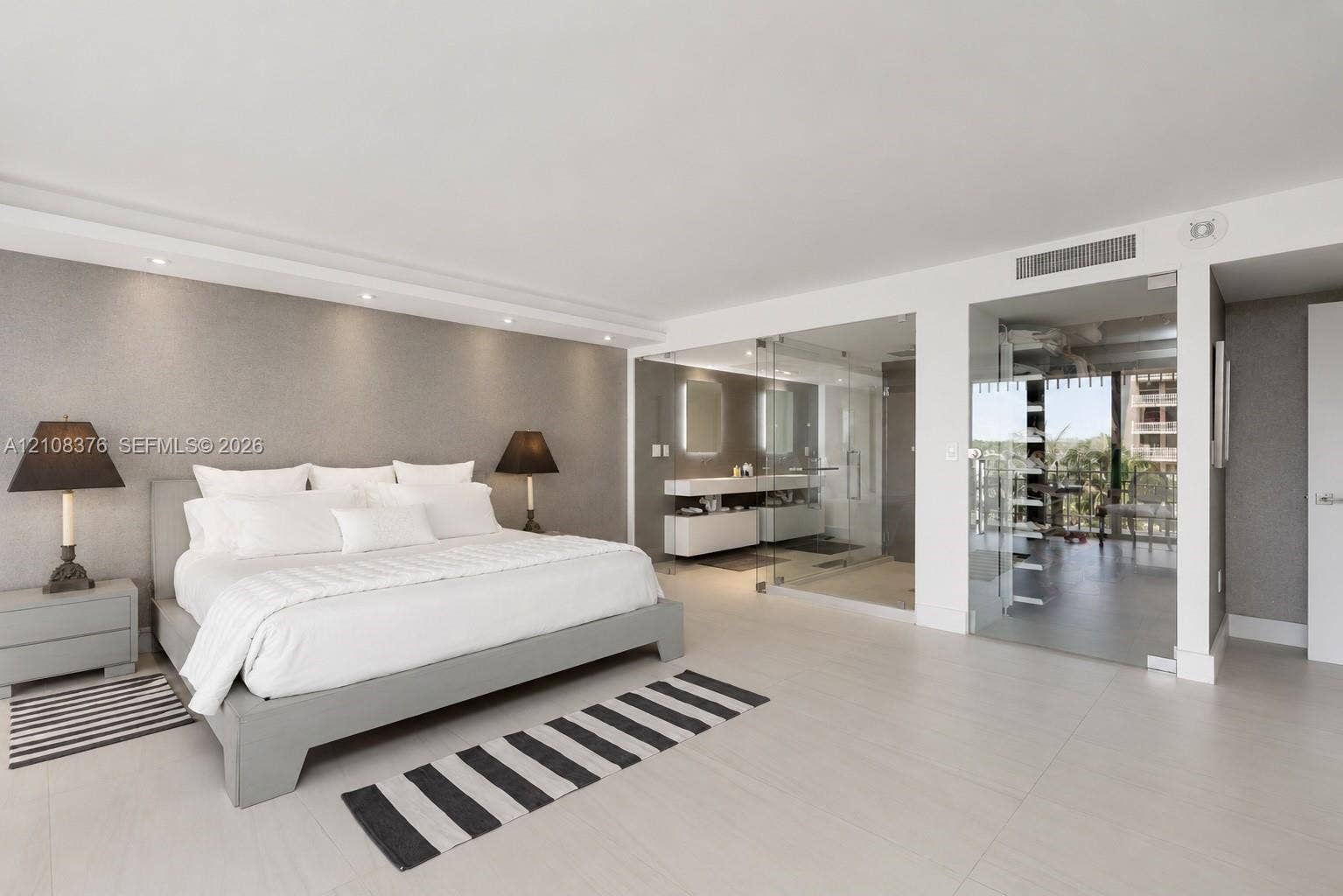 3 Grove Isle Drive, #C502, Miami, Miami, FL 33133 Neutral-toned interior space featuring large-format tile flooring, recessed ceiling lighting, textured accent wall, and glass-enclosed bathroom area