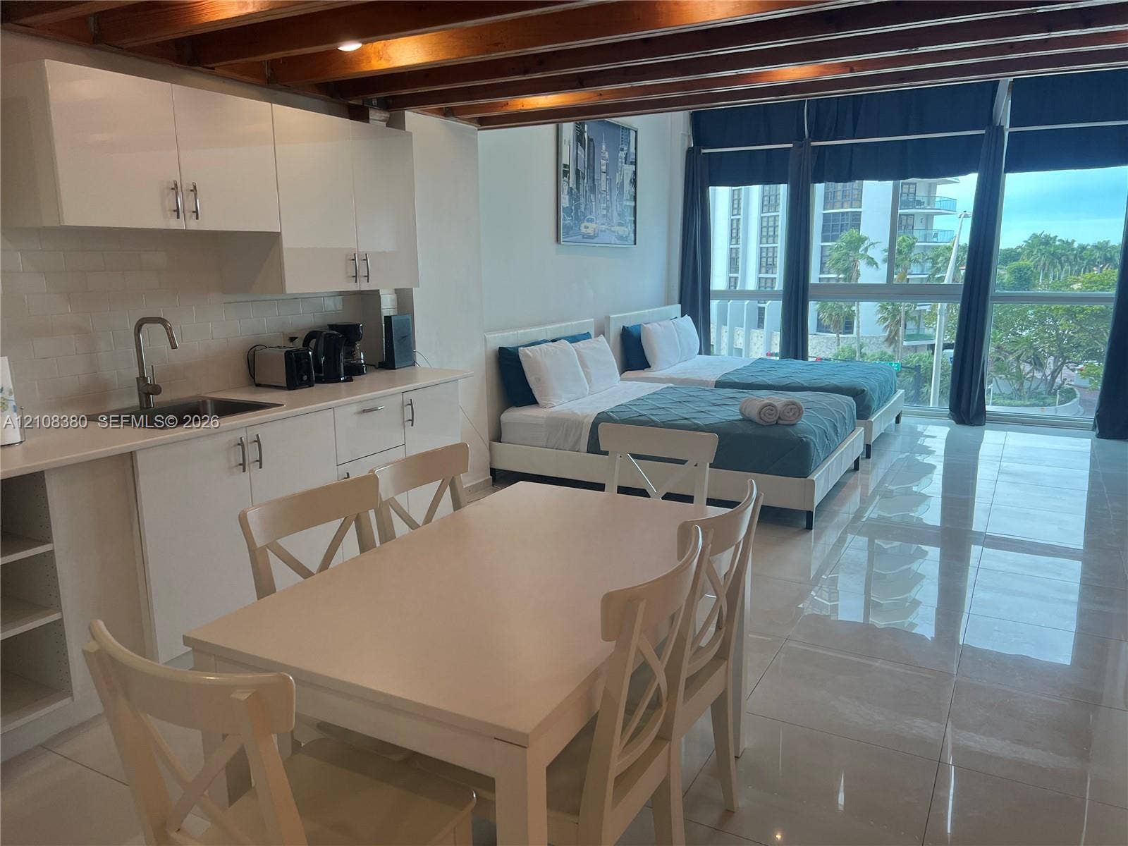 5445 Collins Avenue, #BAY11, Miami Beach, FL 33140 Kitchenette featuring white slab-panel cabinetry, white solid-surface countertops, and a subway tile backsplash