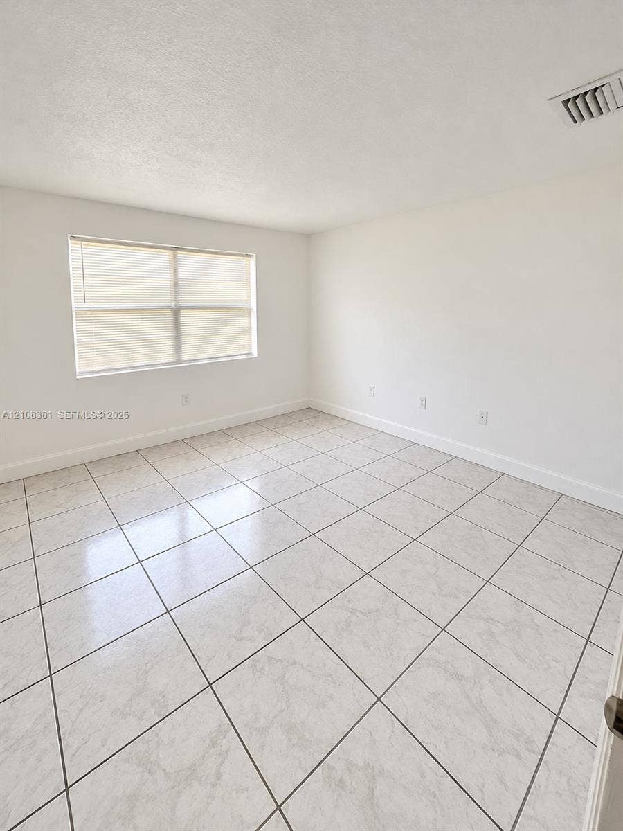 621 NW 177th Street, #101, Miami Gardens, Miami Gardens, FL 33169 Interior space featuring neutral white walls and square stone-finish tile flooring