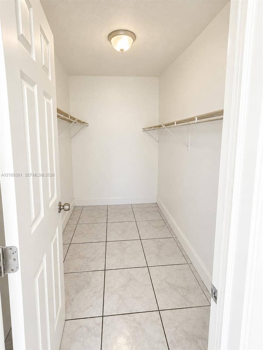 621 NW 177th Street, #101, Miami Gardens, Miami Gardens, FL 33169 Neutral interior space featuring stone-finish tile flooring, white wall finishes, and a single window with blinds
