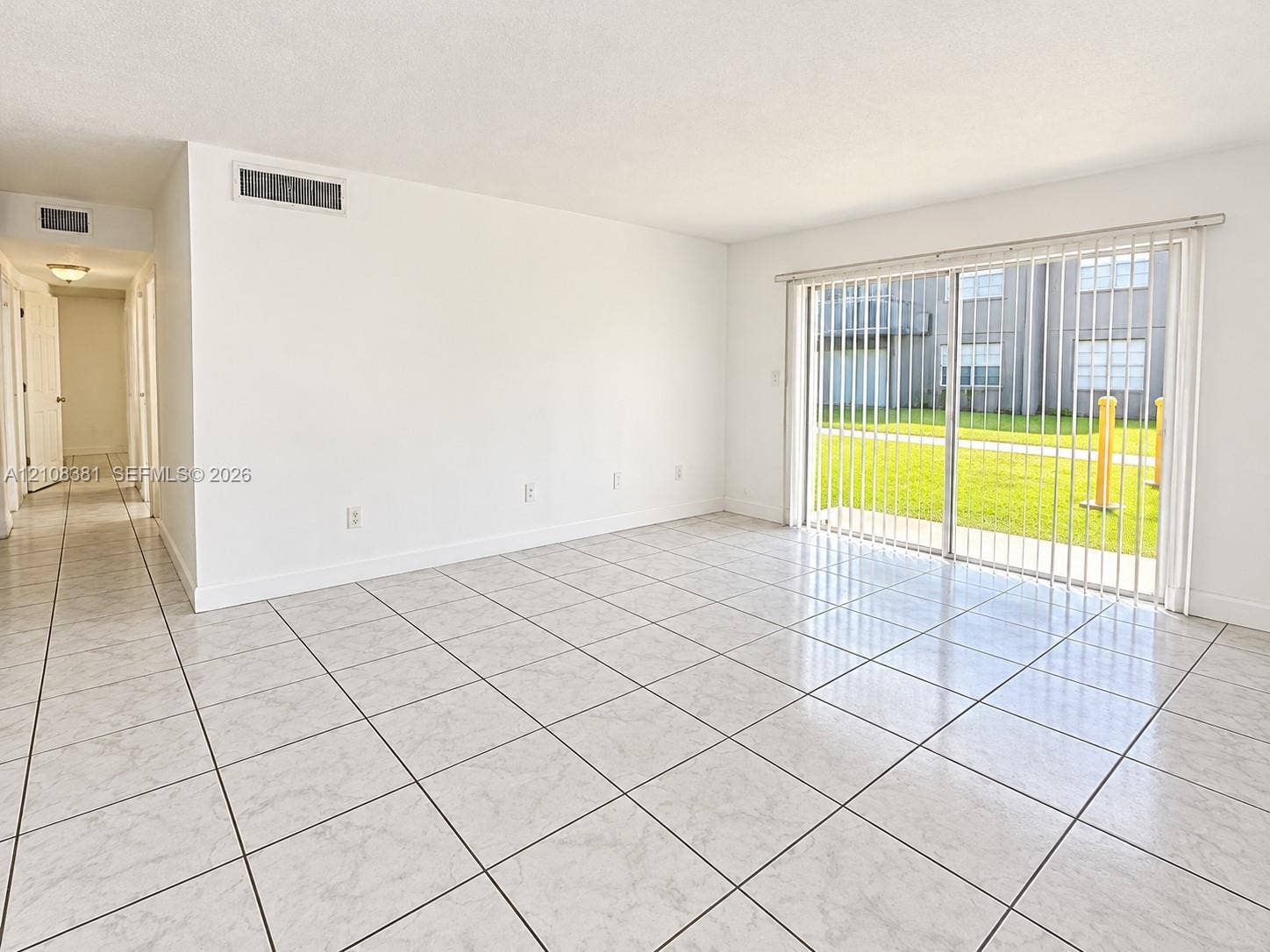 621 NW 177th Street, #101, Miami Gardens, Miami Gardens, FL 33169 Neutral interior space featuring polished tile flooring, smooth white walls, and a large sliding glass door with vertical blinds
