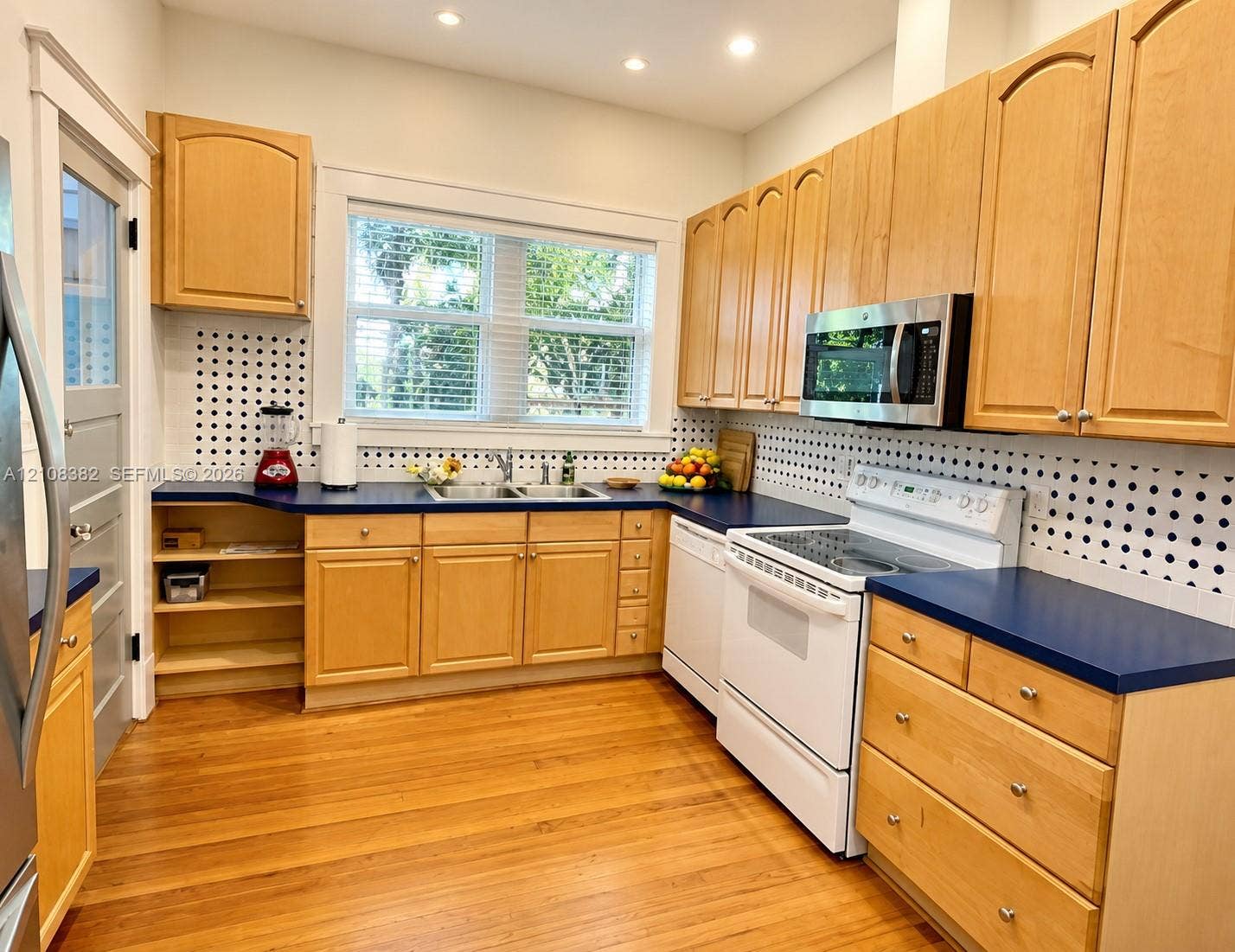 1701 S Olive Avenue, West Palm Beach, FL 33401 Kitchen featuring natural wood cabinetry, blue countertops, a double basin stainless steel sink, recessed lighting, and wood-finish flooring