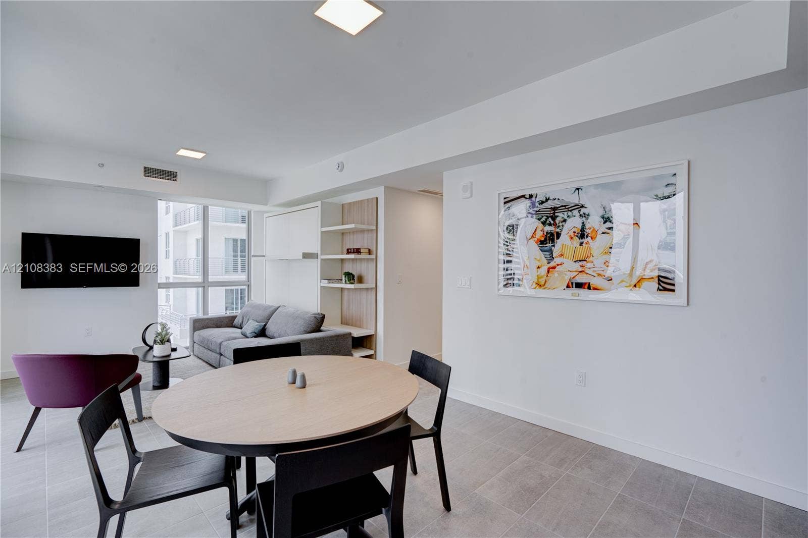 Open-concept area featuring tile flooring, floor-to-ceiling windows, recessed square lighting, and built-in wood-tone shelving